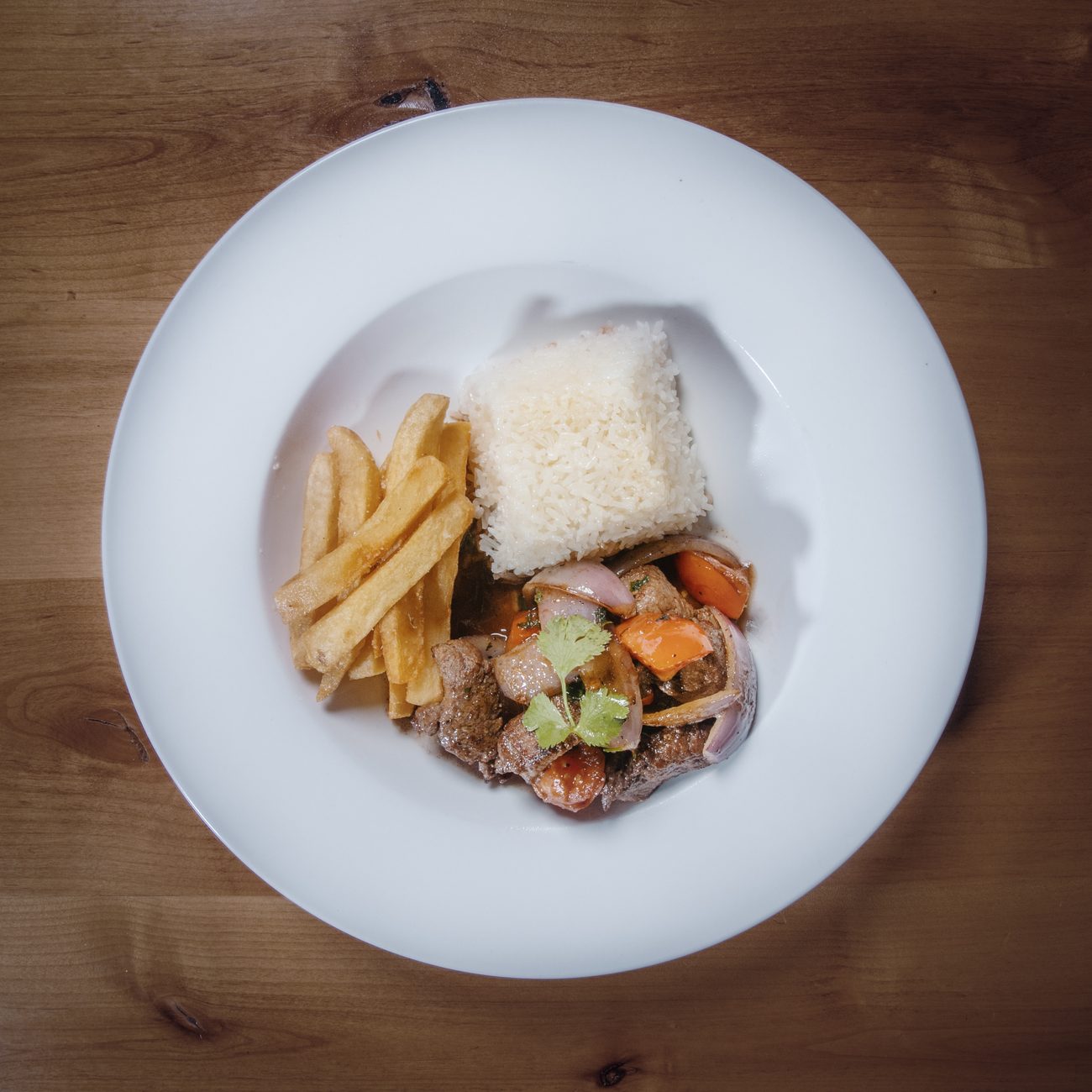 Lomo saltado — sautéed beef with onion and tomato, rice and fries.